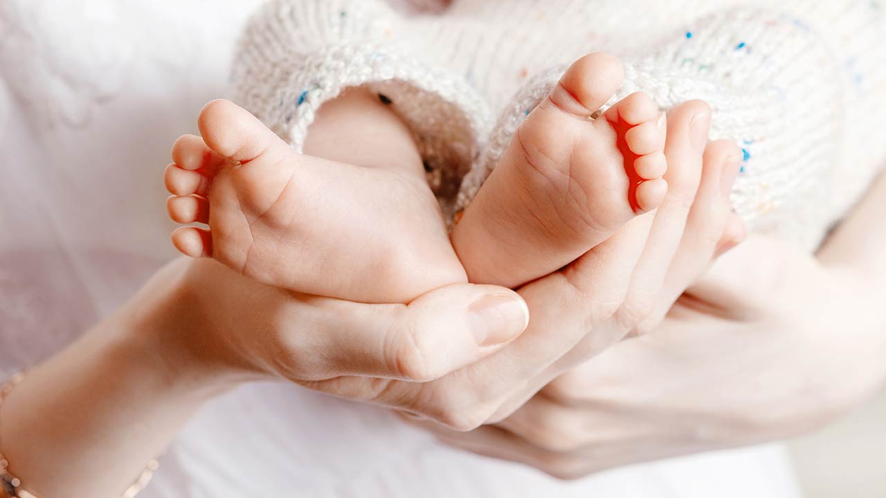 Photo of a tiny Newborn Baby's feet on female Heart Shaped hands
