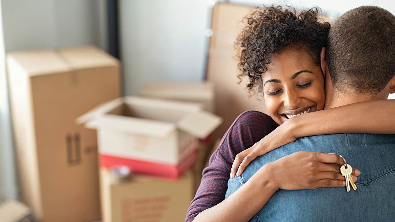 Woman holding keys from new home and embracing man