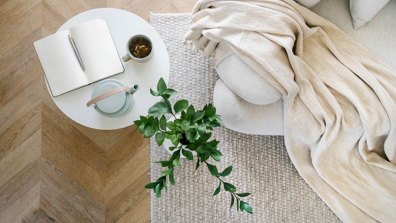 Overhead view of an open book, plant, tea and couch in living room interior design