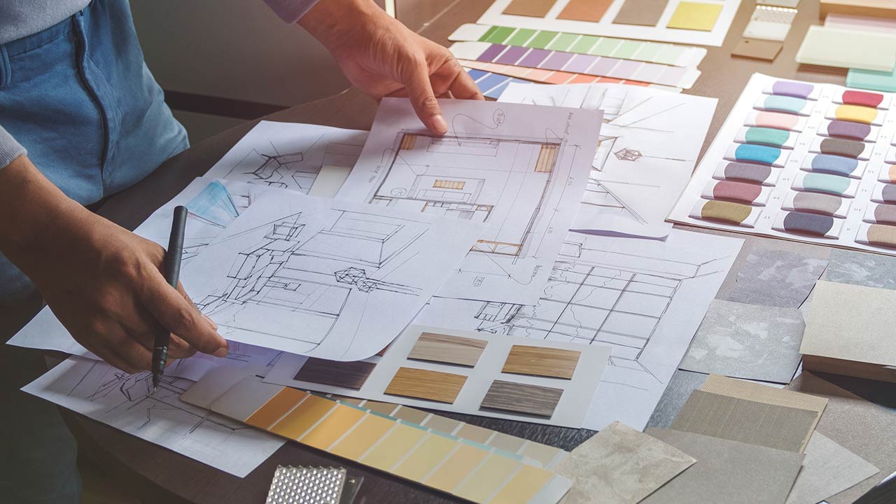 Interior designer working on hand drawing sketches on plan blueprints