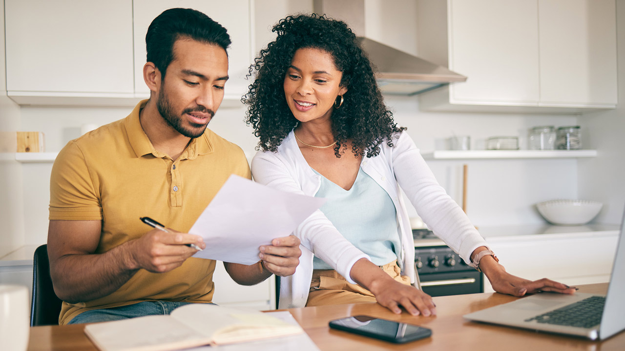 Couple reviewing financial documents at a kitchen counter